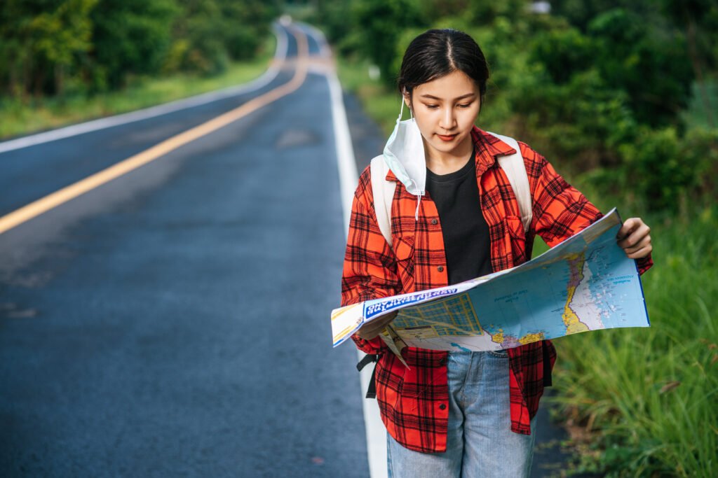 female tourists stand and look at the map on the road.