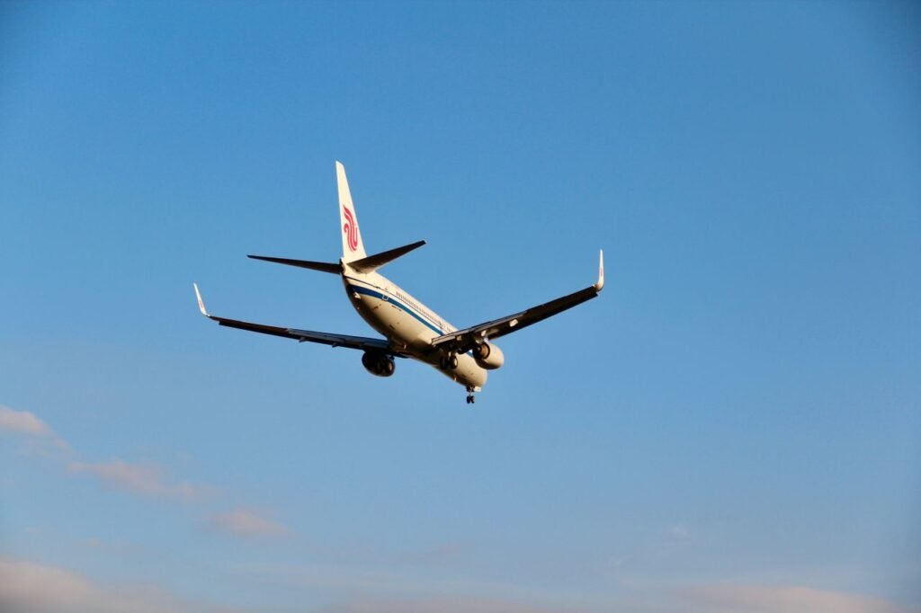 Best Time to Book Flights for Maximum Savings A commercial jet airliner in flight against a clear blue sky, captured from behind.
