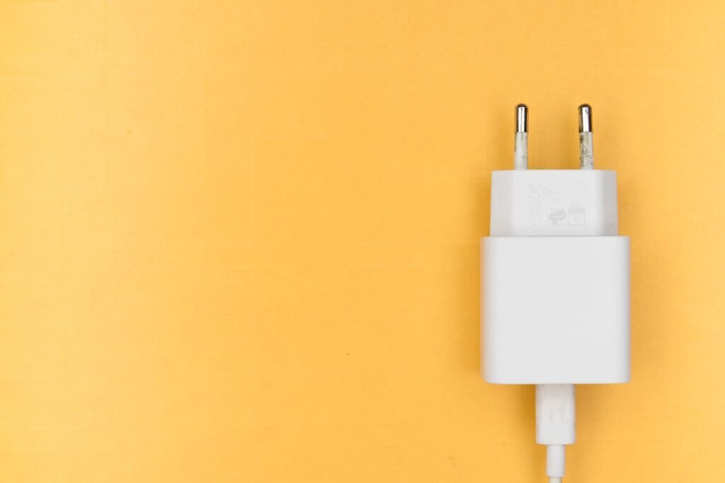 A minimalist image of a white charger against a bright yellow background, perfect for tech themes.